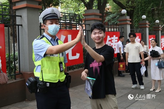 6月7日8時許，武漢中學(xué)考點門口，交警在維護秩序，并?？忌鸢耦}名。人民網(wǎng)記者 肖璐欣攝