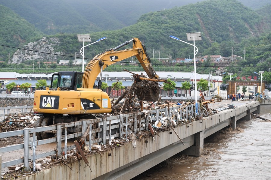 8月1日，在北京市門頭溝區(qū)水峪嘴村村口，一臺挖掘機(jī)在清理阻斷橋梁交通的雜物。目前該條道路已經(jīng)疏通完成。新華社記者 鞠煥宗 攝