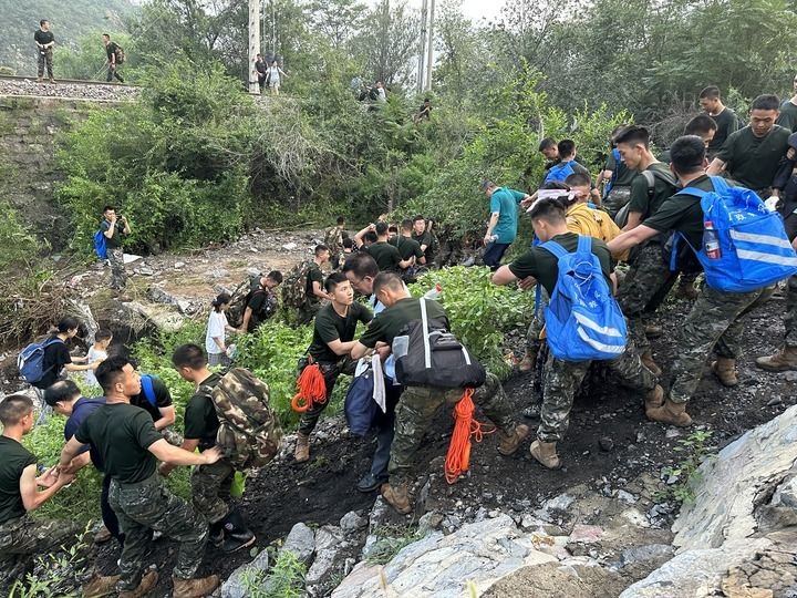 8月2日，Z180次受困列車(chē)的旅客在武警北京總隊(duì)機(jī)動(dòng)第三支隊(duì)官兵的幫助下徒步前往轉(zhuǎn)運(yùn)客車(chē)（手機(jī)照片）。新華社記者 王艷剛 攝