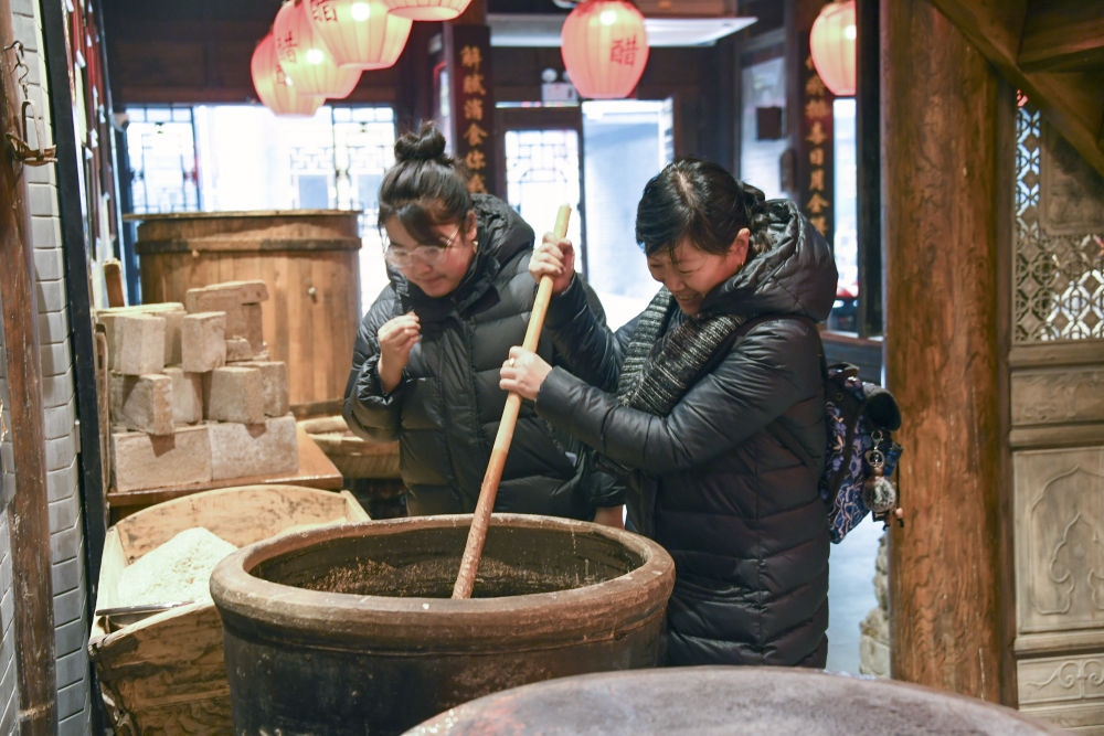 游客在平遙古城東湖老醋坊內(nèi)體驗(yàn)陳醋發(fā)酵打耙（2022年1月28日攝）。新華社發(fā)（梁生仁攝）