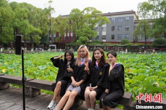 6月19日，時值一年畢業(yè)季，四川大學(xué)望江校區(qū)荷花池里的荷花盛開，成為了畢業(yè)生們的打卡圣地，吸引了眾多畢業(yè)生拍照留念。圖為畢業(yè)生在荷花池邊拍照留念。中新社記者 安源 攝