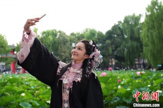 6月19日，時值一年畢業(yè)季，四川大學(xué)望江校區(qū)荷花池里的荷花盛開，成為了畢業(yè)生們的打卡圣地，吸引了眾多畢業(yè)生拍照留念。圖為畢業(yè)生在荷花池邊拍照留念。中新社記者 安源 攝