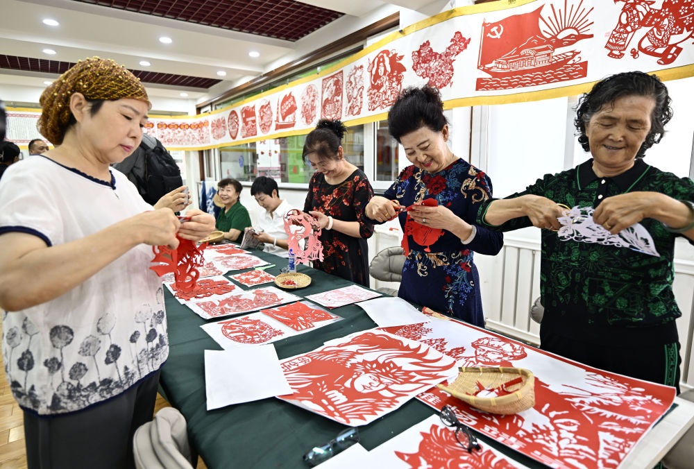 6月19日，長城花園社區(qū)居民在社區(qū)“才藝堂”制作剪紙。