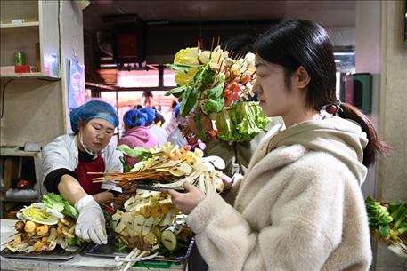 游客挑選好麻辣燙菜品后排隊等待加工。新華社記者 范培珅 攝