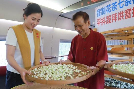 10月1日，福州市茉莉花茶窨制工藝代表性傳承人張子建與旅客在G1634次列車上制作茉莉花茶。新華社記者周義 攝