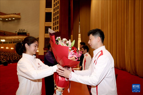 11月15日，一名學(xué)生代表在報告會上向乒乓球運動員馬龍（右）獻花。新華社記者 李明 攝